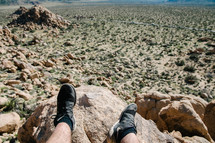 a man sitting on a rock looking out at the desert 