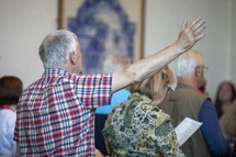 an elderly man with hand raised in praise during a worship service 