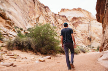 A man walking along a path in a canyon.