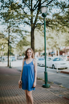 a young woman standing on a brick sidewalk downtown 