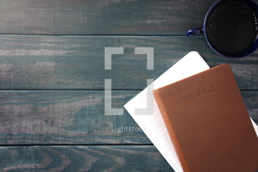 leather Bible, notebook, and coffee cup on a wood background 