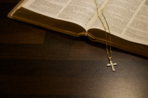 cross necklace over the pages of a Bible 
