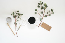 coffee cup, gift tag, eucalyptus twigs, pencil, votive, scissors, candle