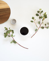 eucalyptus twigs, coffee cup, wooden lazy Susan, votive candle 