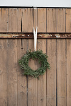 An evergreen wreath hanging on an old wooden gate.