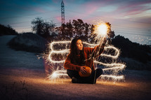 a woman holding a pumpkin playing with a sparkler 