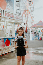 a teen girl at a fair standing by a ticket booth 