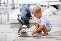 Boy holding a rope on a pier.