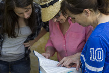 Three women looking at a passage in the Bible.