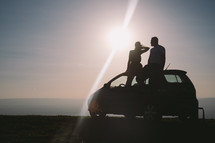 silhouette of a couple sitting on a car 