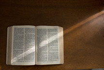 A Bible open to the Book of Isaiah on a wood surface.
