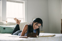 young woman reading a Bible on her bed 