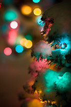 bokeh Christmas lights and a Christmas tree covered in snow