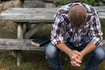 a man praying at a picnic table 