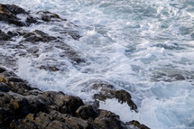 rocky shore and froth on ocean water 