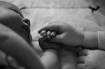 a sister holding her babies brother's hand 