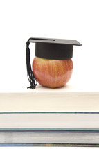 graduation cap on an apple on a stack of books 