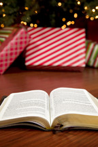 open Bible on the floor in front of a decorated Christmas tree 