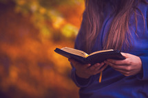 Reading the Bible in an autumn forest