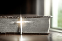 silver cross in front of a Bible 