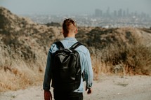 young man with a backpack and distant city 