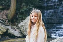 smiling child in front of a waterfall 