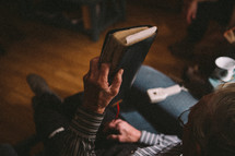 a man reading a Bible in a chiar 