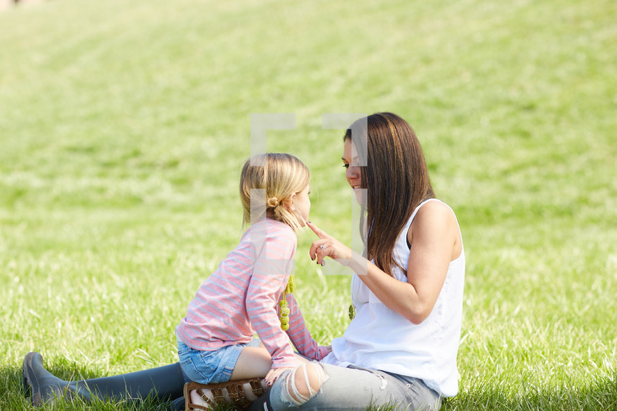 a mother and daughter sitting in the grass