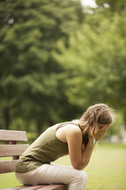 Worried woman sitting on park bench.