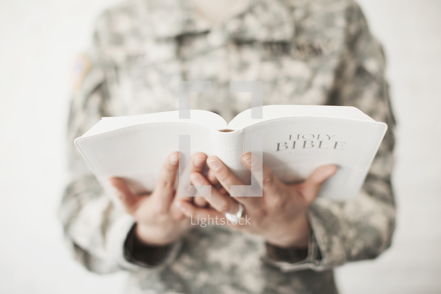 Female soldier in uniform holding a Bible.
