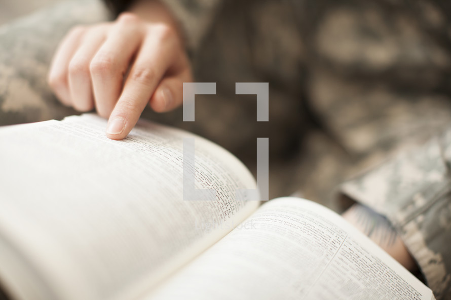 Female soldier in uniform reading the bible.