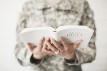 Female soldier in uniform holding a Bible.