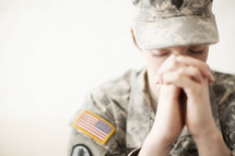 Female soldier in uniform praying.