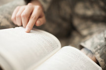 Female soldier in uniform reading the bible.
