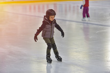 child ice skating with a helmet on 