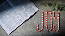 Candy canes spelling joy next to Bible