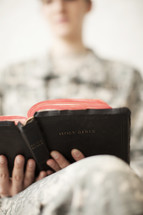 Female soldier in uniform reading the Bible.