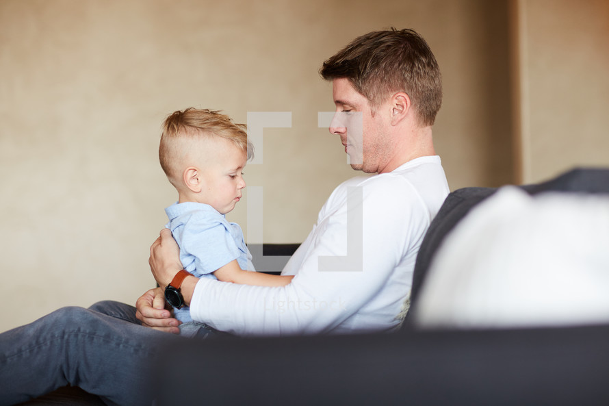 a father holding his son on a couch 
