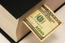 one hundred dollar bill bookmark in a Bible 