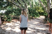 woman walking into a coastal jungle 
