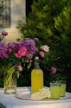 A Bottle and Glasses Of Homemade Lemonade Made From Elderberry Syrup on Table
