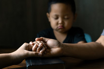 Asian child praying with his family