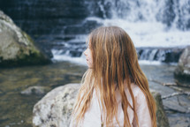 child standing in front of a waterfall 