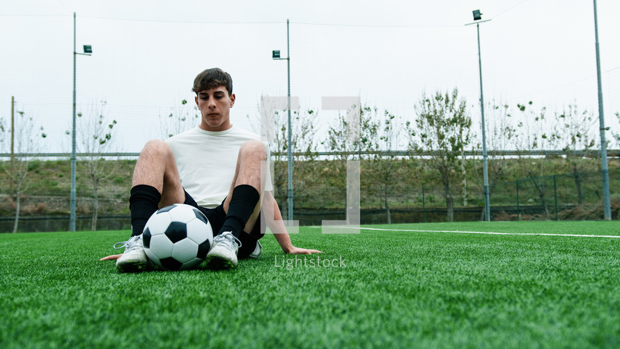 Teenage Soccer Player Sitting on the Side of the Field Breathing Tired