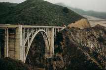  a bridge connecting two mountains by the ocean 