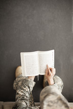Female soldier in uniform reading the Bible.