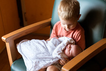 a child holding his newborn sibling 
