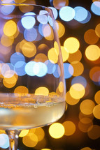 Gold and white bokeh lights with wine glass