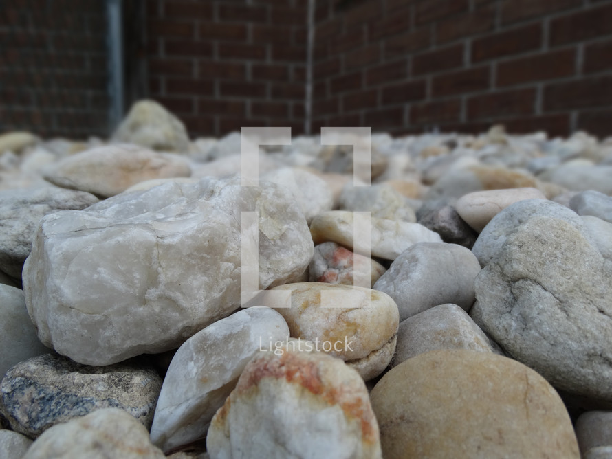 White and beige rocks in rock bed beside house in lawn