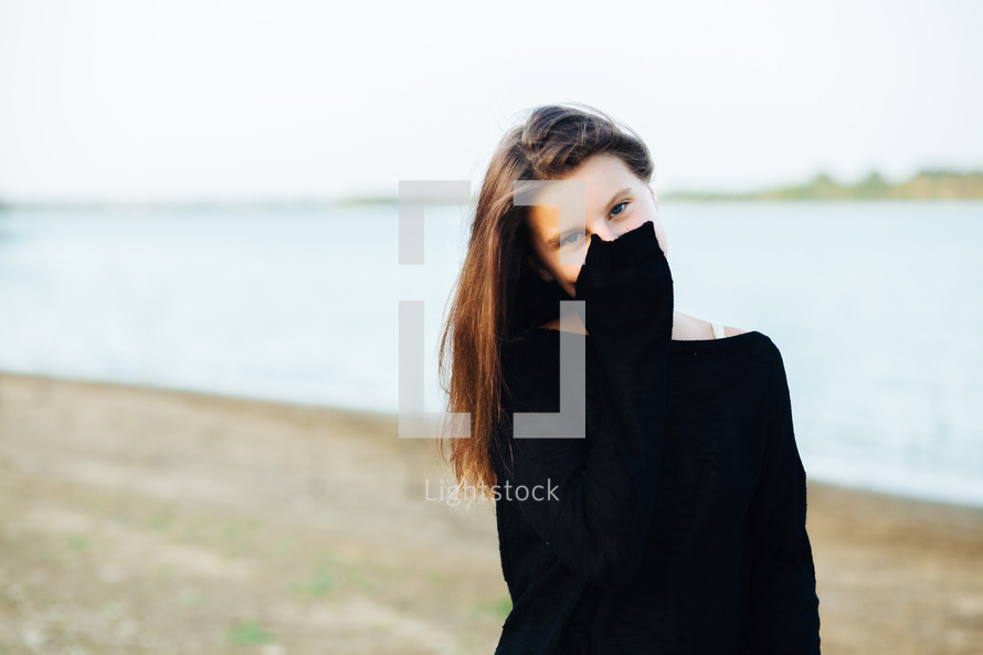 a teen girl covering her face with her sleeve 